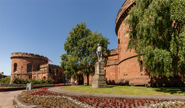 Photo of a statue, trees and flowerbeds outside castle grounds