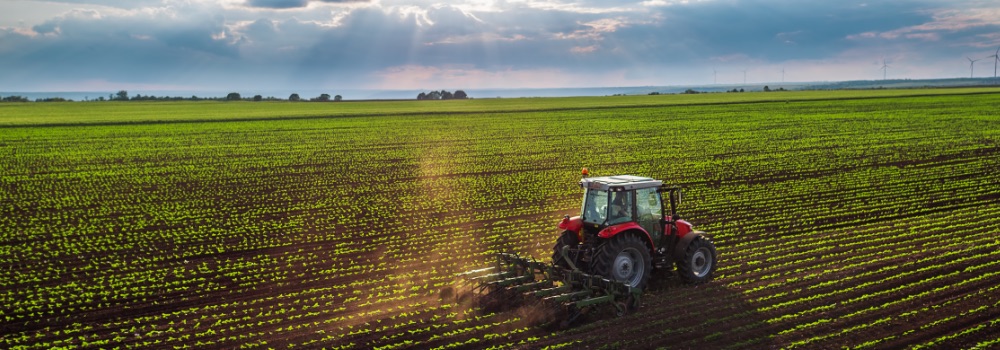 Wide angle photo of a tractor ploughing vast farmland