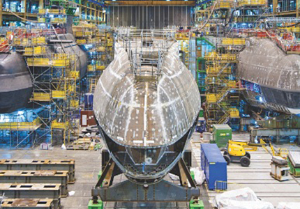 Photograph of a busy aerospace construction hanger with aeroplane shell